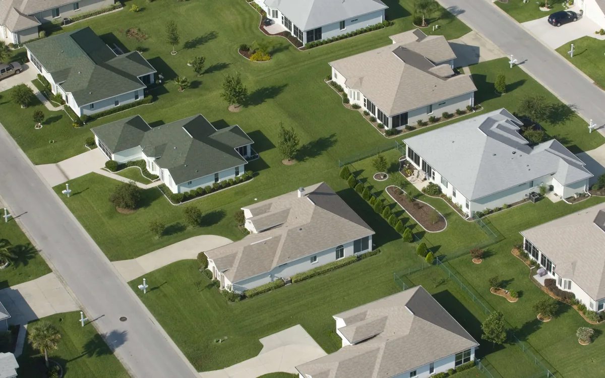 An aerial view of a suburban street of detached houses with lawns