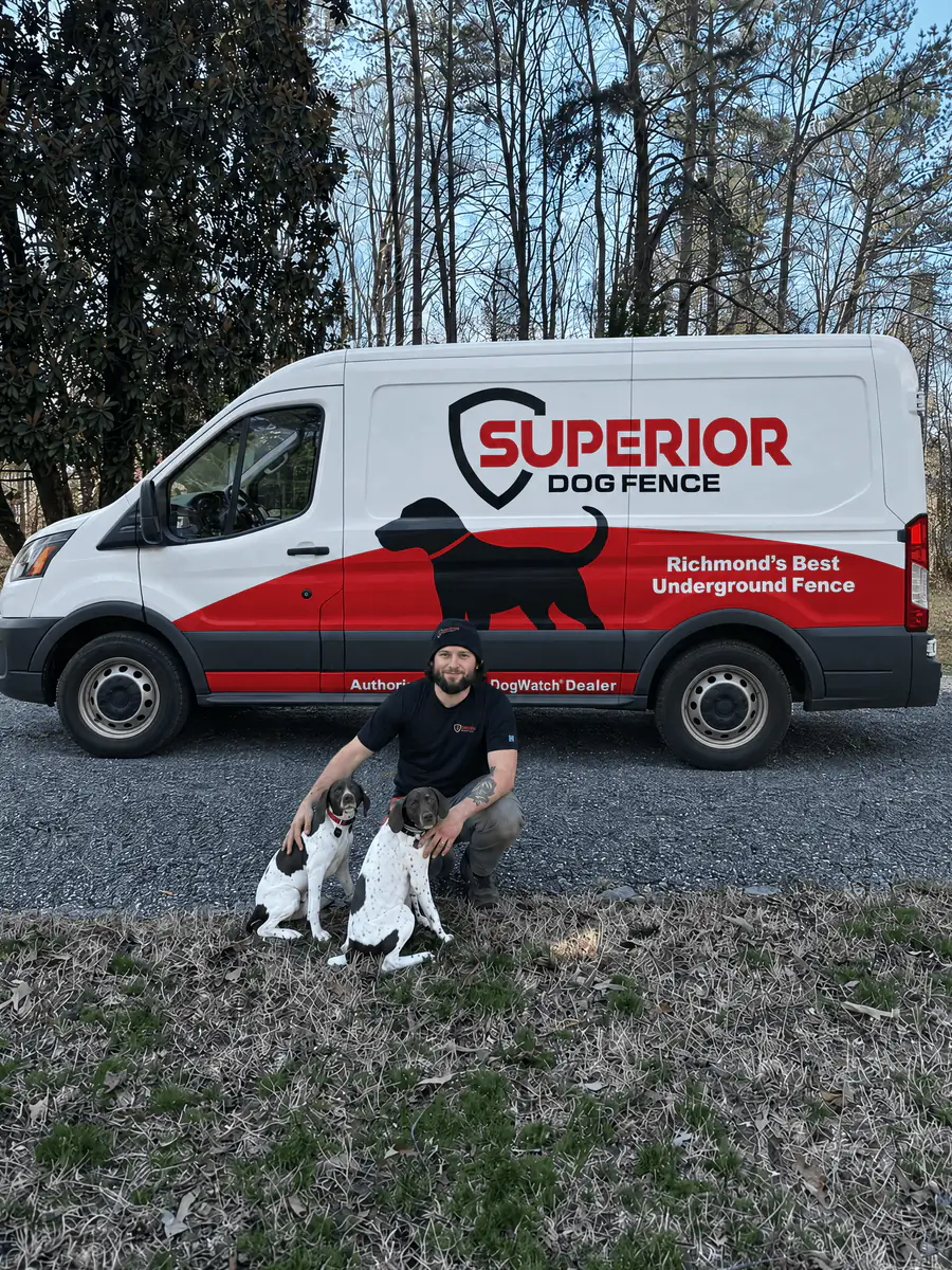 Two people kneeling with a litter of puppies beside the Superior Dog Fence van