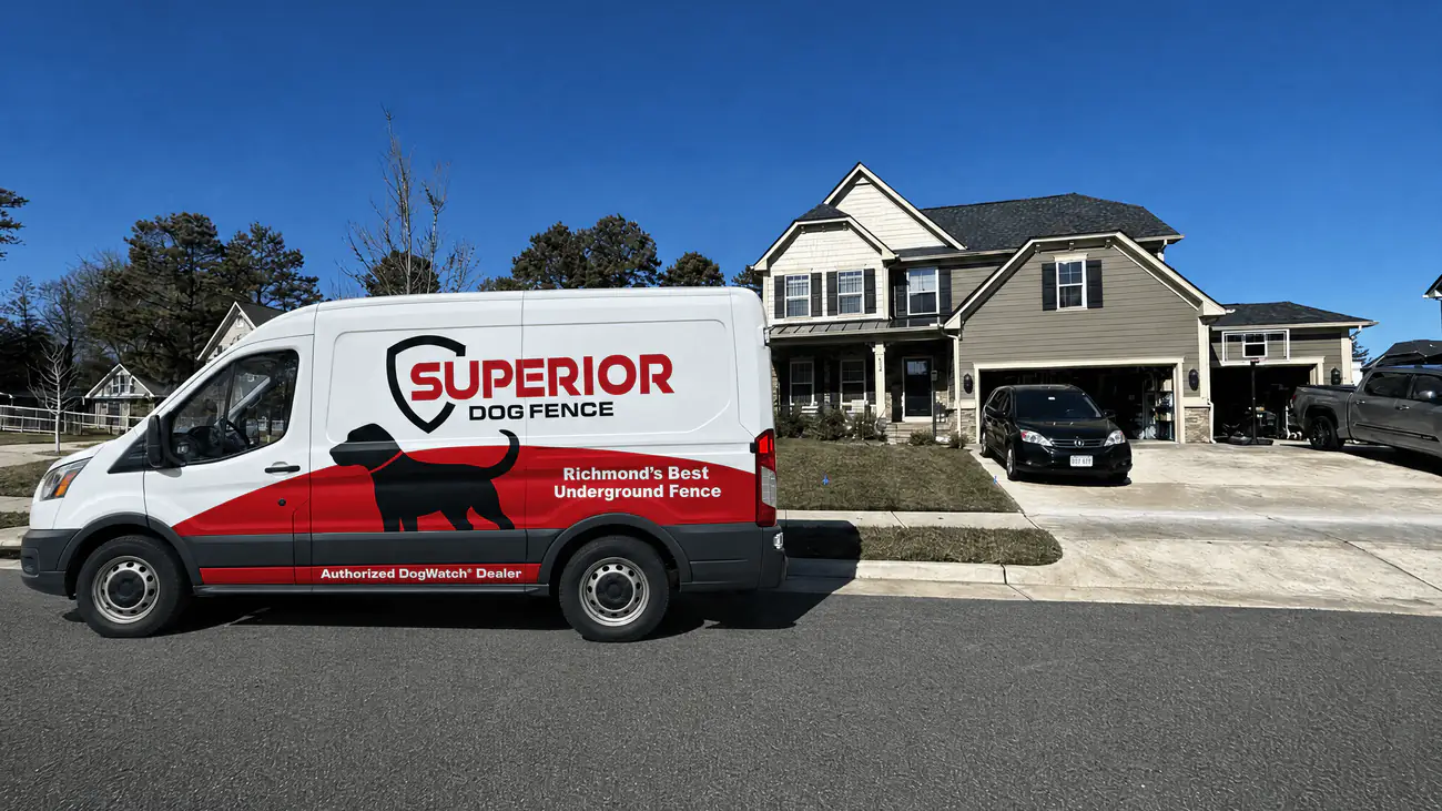 The Superior Dog Fence van parked outside a suburban home under a clear sky.